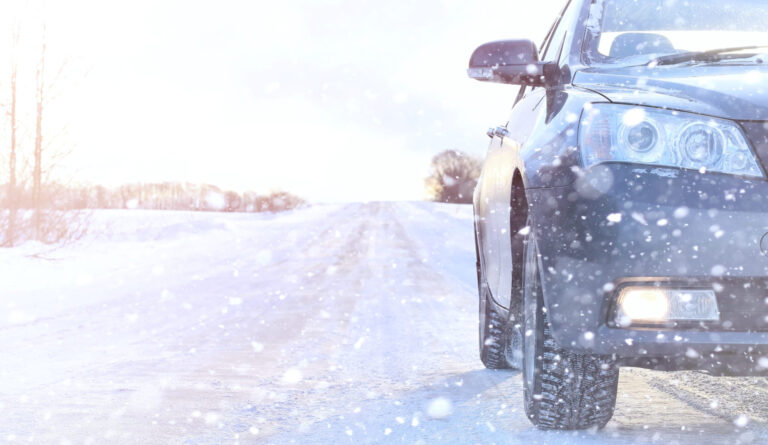 Osobné auto brzdiace na zasneženej zimnej ceste s klzkým povrchom a predĺženou brzdnou dráhou.
